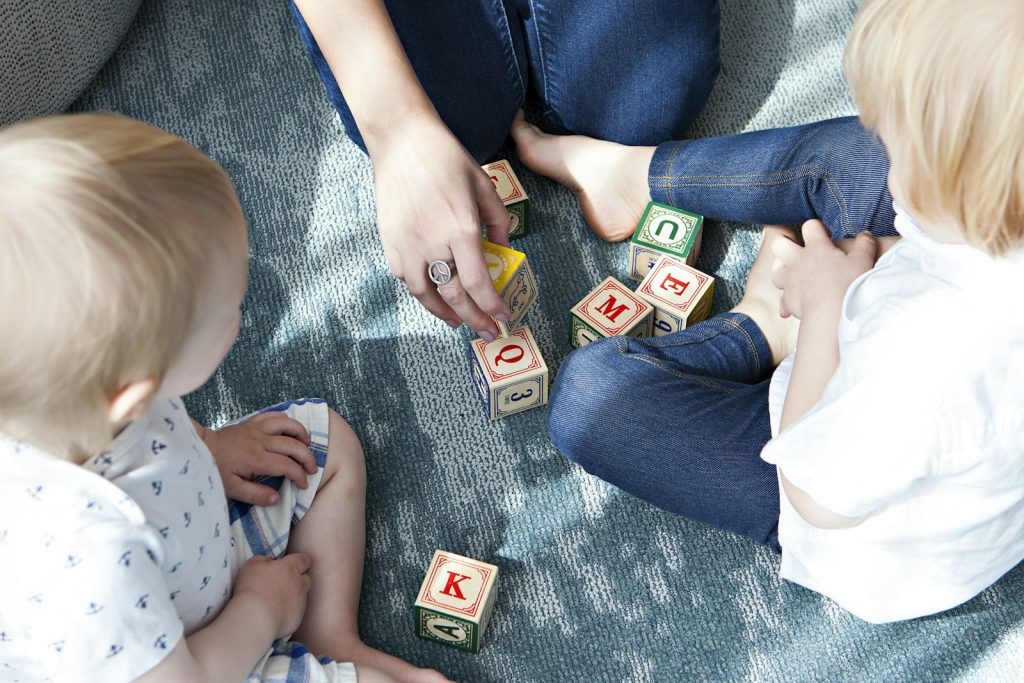 Bambini e adulta giocano insieme con costruzioni di legno